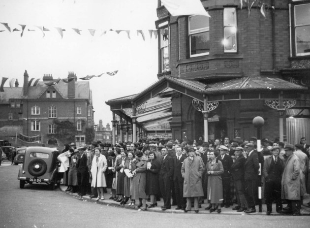 Photo of the throngs of spectators the ISDT attracted to Llandrindod Wells each year. Here crowds gather near the start finish where  Hraham Walker, editor of Motor Cycling and father of Murray Walker Famous for his F1 sports commentaries announces on the arrival of riders. ISDT 1938
