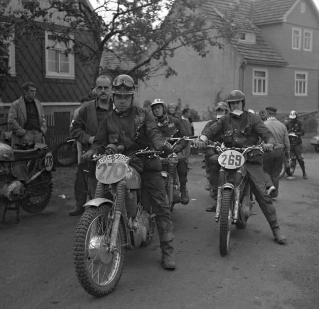 Photo Riders at unknown time check a trio of British riders include #270 Arthur Bates AJS 550 [BGC 978 B] of the GB Silver Vase 'B' Team #269 AS Jones Matchless 584 #279 Ken Heanes Triumph 649 behind Arthur staring into the sky is #278 Steve McQueen