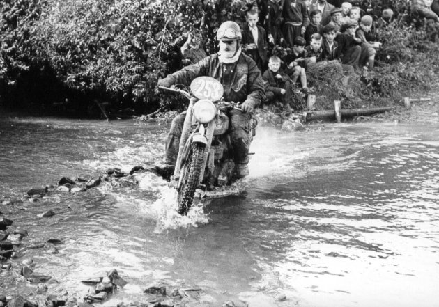 Photo - #253 Bob Ray crosses a ford whilst onlooked by a large crowd of young spectators ISDT 1955