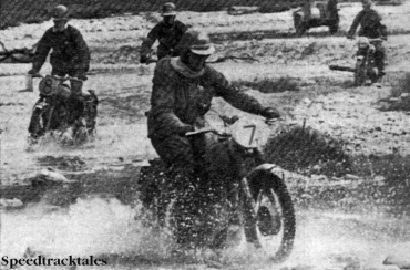 Photo- Four British riders splash across the waters of the River Isar, in desolate country. Trophy man #7 Tim Gibbes (AJS) is leading, followed by privateer #8 Eric Chilton (Triumph), Silver Vase teamster #11 Vic Eastwood (AJS) and top-scoring Trophy member #10 Johnny Giles (Triumph) ISDT 1962 (Speedtracktales Collection)