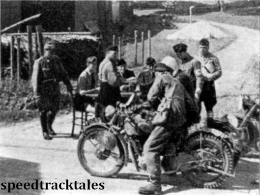 Photo - A typical scene at a check with Nazi's operating the control and a policement looking on #6 is Capt GM Barry of the British Army Norton Team. ISDT 1939 (Speedtracktales Archive)