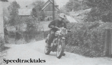 Photo - Bend-swinging his Triumph through Altaussee on the Wednesday, Ken Heanes drops a precautionary foot as the back wheel steps out ISDT 1960