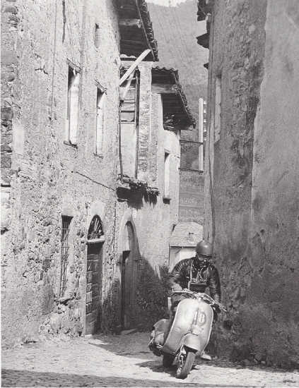 Photo of Scooter Rider passing through narrow streets in a town ISDT 1951