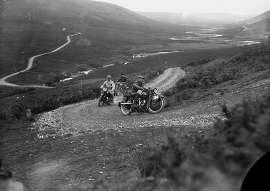 Photo by P B Abery titled ‘Motorcycle racing in Rhayader on the old road to Aberystwyth’. The image may be from the ISDT 1933 with riders #124 A P Van Hamersveld 499cc Rudge Holland - Rtd #128 J Moejas 597cc Ariel Holland - Silver #129 H Kelly 497cc Ariel GB - Rtd. (Image Courtesy of the P B Abery Collection, National Library of Wales)