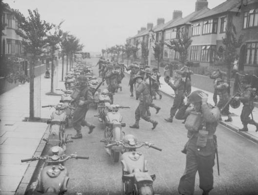 Photo - A 'fighting column' from the South Wales Borderers man their motorcycles which are parked in a suburban street in Bootle, Liverpool, England, 16 August 1940. This training operation formed part of British preparations to repel the threatened German... (Image courtesy Imperial War Museum)
