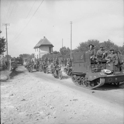 Photo - Universal carriers and motorcycles driving inland from Arromanches during the build-up of Allied reinforcements in the bridgehead, 22 June 1944. (Image courtesy Imperial War Museum)