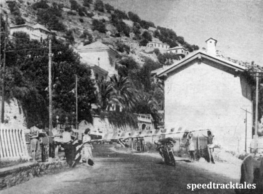 photo - A Crash-hatted competitor ducks under the barrier at a level-crossing on the main Genoa railway line. Competitors are helped in this way while ordinary traffic was held up. ISDT 1948 (Speedtracktales Collection)